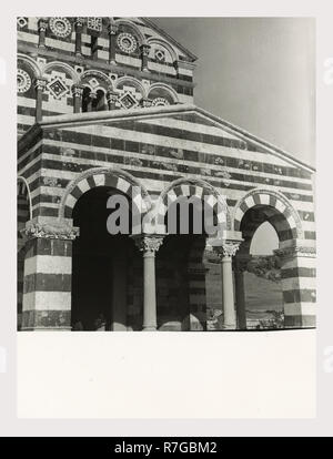 Sardinien Sassari Sassari Umgebung SS. Trinità di Saccargia Camaldolite, das ist mein Italien, die italienische Land der visuellen Geschichte, Außenansichten einer romanischen Kirche aus dem 12. Jahrhundert gehören eine gestreifte dunklem Basalt und weißen Kalkstein Fassade ein Turm von Pisa und Lucchesian Einfluss und dekoriert/groteske Hauptstädte. Antiquitäten zwei Säulen und Kapitelle des Portikus. Foto 1983 Stockfoto