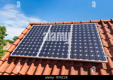 Reihe mit drei blauen Sonnenkollektoren auf dem Dach des Hauses Stockfoto