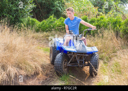 Jungen kaukasischen Mann fahren Quad durch sandigen Kurve Stockfoto