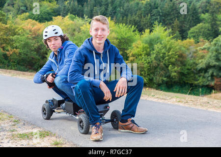 Zwei junge holländische Männer sitzen zusammen auf mountainboard in der Natur Stockfoto