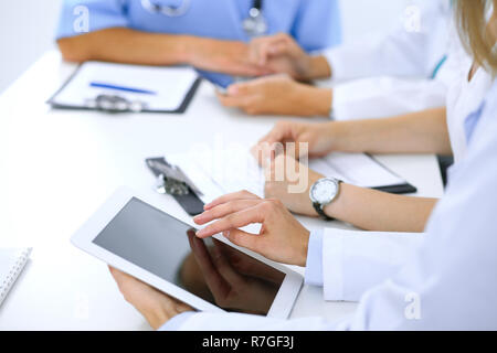 Arzt mit Tablet-PC auf medizinische Konferenz, Nahaufnahme. Gruppe von Kolleginnen und Kollegen in den Hintergrund Stockfoto