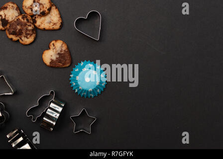 Cookies, Backformen, Schutzpapier auf schwarzem Hintergrund Stockfoto