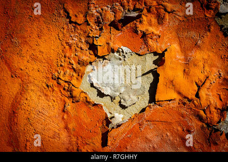 Orange Putz blättert von einer alten Mauer. Alt, dreckig geschält Pflasterwand mit aus fallenden Flocken von Farbe. Textur, Muster, Hintergrund. Stockfoto