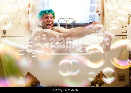 Fetter hässlicher Mann waschen in der Badewanne. Bizarre männliche Person im Bad lachen Stockfoto