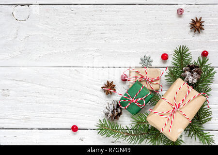 Weihnachten Hintergrund mit Tannenzweigen, Dekorationen, Geschenkverpackungen und Tannenzapfen auf weissem Holztisch. Weihnachten Hintergrund. Flach. Ansicht von oben mit Co Stockfoto