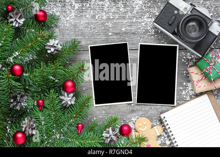 Retro Kamera und Weihnachten leeren Bilderrahmen mit Fir Tree Branches, Dekorationen, Geschenkverpackungen und gefütterte Notebook über rustikal Hintergrund. mock u Stockfoto