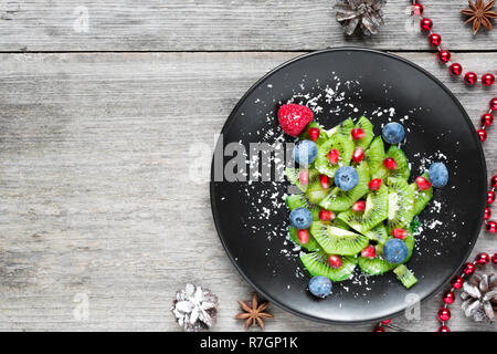 Kiwi Weihnachtsbaum. Lustig essen Idee für Kinder. Weihnachten und Neujahr essen Hintergrund. top View Stockfoto