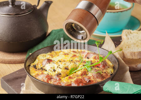 Leckeres Frühstück Shakshuka in eine eiserne Pfanne. Spiegeleier mit Tomaten, Zwiebel, Petersilie, Brot und Kräutern. Gesunde Ernährung Stockfoto