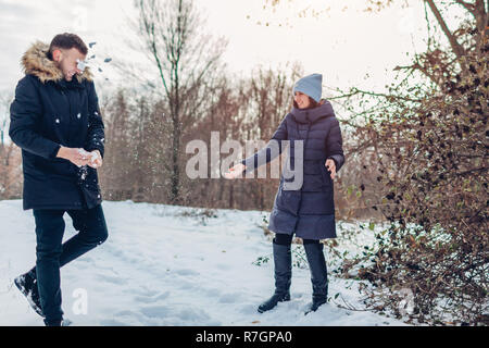 Schöne liebevolle Paare spielen Schneebälle im Winter Wald zusammen. Menschen, die Spaß im Freien. Feiertage Stockfoto