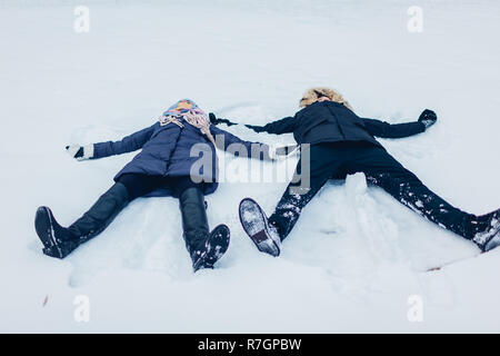 Schöne liebevolle Paar Beschneiung Engel im Winter Wald im Schnee liegen. Glückliche Menschen Spaß im Freien Stockfoto
