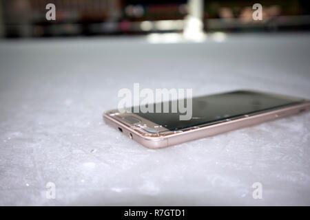 Moderne smart phone mit gebrochenen Bildschirm Glas liegen auf zerkratzte Eis Stockfoto