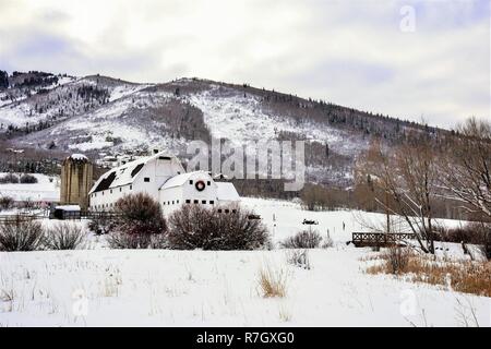 Weiß Molkerei Scheune mit Weihnachten Kranz in eine verschneite Wiese in Park City, UT. Stockfoto