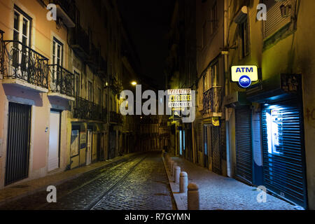 Lissabon, Portugal - Juli 10th, 2018: eine schmale Straße menschenleer und ein Geldautomat Teller Machine Namensschild ausgeleuchtet in der Nacht in Lissabon, Portugal. Stockfoto