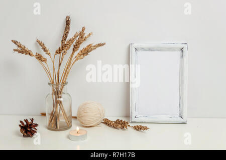 Vertikale Rahmen mockup mit wilden Roggen Blumenstrauß in glass vase in der Nähe von weißen Wand. Leeren Rahmen mock up für Presentation Design. Vorlage framing für moderne Ar Stockfoto