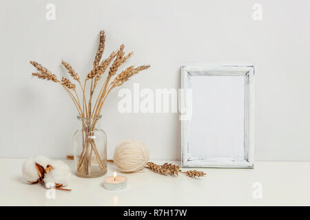 Vertikale Rahmen mockup mit wilden Roggen Blumenstrauß in glass vase in der Nähe von weißen Wand. Leeren Rahmen mock up für Presentation Design. Vorlage framing für moderne Ar Stockfoto