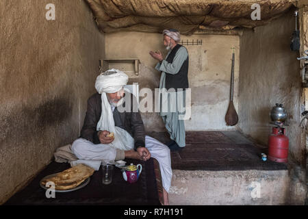 Zwei ältere Männer im Gebet Zeit in einem traditionellen Teehaus im Alten Basar mit RABAB an der Wand hängen, Herat, Provinz Herat, Afghanistan Stockfoto