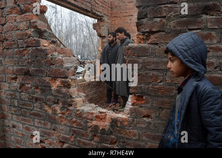 Srinagar, Jammu und Kaschmir, Indien. 9 Dez, 2018. Kaschmirischen Volkes prüfen Krieg verwüsteten Häusern, in denen Aktivisten während der Schusswechsel mit der indischen Regierung Kräfte im Bereich der Mujgund Srinagar, die Hauptstadt des Indischen verwalteten Kaschmir, Indien durchlöchert waren. Vierzehn Jahre alten Jungen unter den drei Kämpfer in die Pistole Kampf getötet. Sechs Wohnhäuser wurden auch beschädigt. Credit: Masrat Zahra/ZUMA Draht/Alamy leben Nachrichten Stockfoto