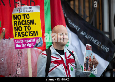 London, Großbritannien. 9 Dez, 2017. Ein Vertreter der Organisation "Fußball gegen Apartheid" hält eine Anti-Facism Zeichen und stellt neben der palästinensischen Flagge. 3.000 15.000 Anti-Facist Pro-Brexit Demonstranten und Gegendemonstranten auf den Straßen von London ihre Haltung in der Frage der Abkommen zu Voice vor der Schlüssel Brexit Abstimmung im Parlament am Dienstag. Credit: Ryan Ashcroft/SOPA Images/ZUMA Draht/Alamy leben Nachrichten Stockfoto