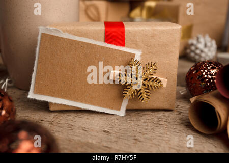 Vintage Geschenkbox (Package) mit leeren Geschenkanhänger auf alten Holz- Hintergrund, xmas dekorative Elemente. Weihnachten festliche Close up, kopieren Raum Stockfoto