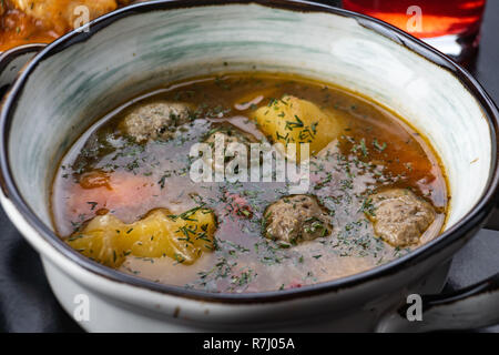 Suppe mit Fleisch, Kartoffeln und Gemüse. in einer weißen Platte auf schwarzem Hintergrund Stockfoto