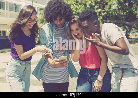 Internationalen Gruppe von jungen Erwachsenen spielen mit Telefon im Freien in der Stadt Stockfoto