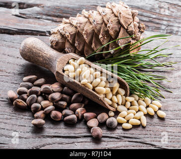 Pinienkerne in die Schaufel und Pinienkernen Kegel auf dem Holztisch. Ökologische Lebensmittel. Stockfoto