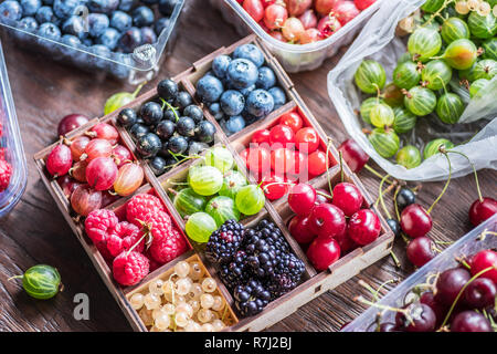 Bunte Beeren in der Holzkiste auf dem Tisch. Ansicht von oben. Stockfoto