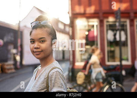 Lächelnde junge asiatische Frau steht auf einer Straße der Stadt Stockfoto