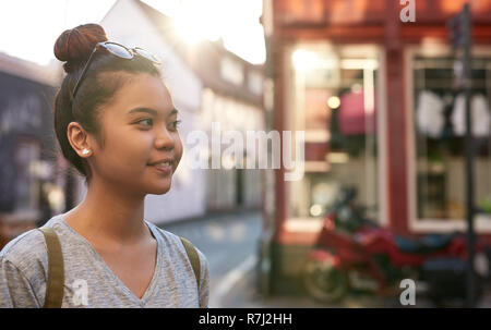 Junge asiatische Frau lächelnd beim Gehen in der Stadt Stockfoto