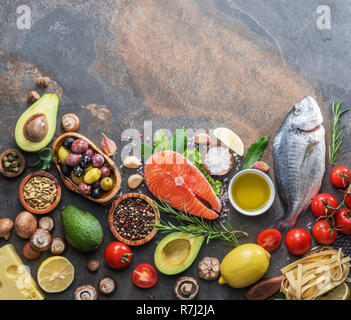 Raw dorado Fisch und Lachssteak mit Gewürzen und Gemüse auf dem Graphit. Ansicht von oben. Stockfoto