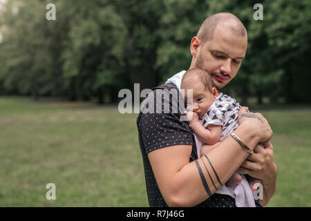 Liebevolle junge Vater außerhalb schaukelnd seine adorable Baby Boy Stockfoto