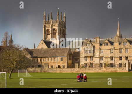 Oxford Schuljungen Praxis Fußball auf Merton Feld Spielfeld mit Merton College hinter und dunklen Gewitterwolken Stockfoto