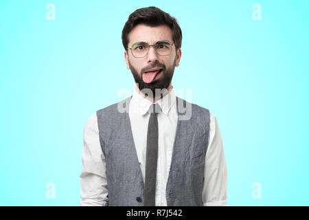 Junge Mann trägt weißes Hemd und Weste beleidigt fühlt, zeigt Zunge Stockfoto