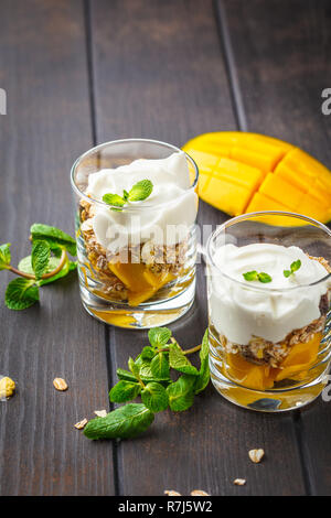 Griechischer Joghurt mango Müsli Parfait in einem Glas auf einem dunklen Hintergrund. Stockfoto