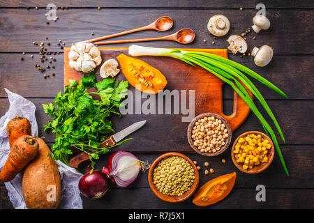 Zutaten für pflanzliche vegane Suppe mit Linsen, Pilze und Kichererbsen auf einem dunklen Hintergrund, Ansicht von oben. Stockfoto