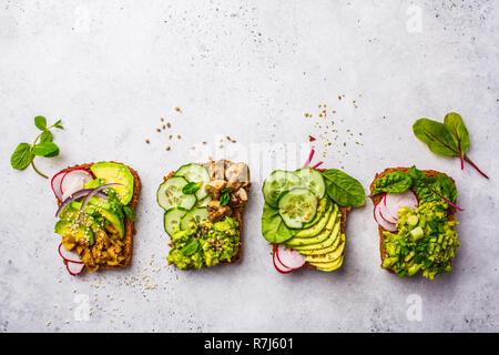 Avocado Toast mit verschiedenen Belägen, Ansicht von oben, weisser Hintergrund. Auf Basis pflanzlicher Ernährung Konzept. Stockfoto