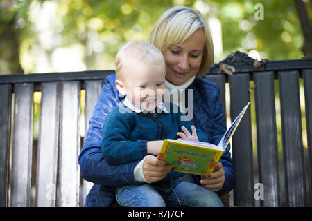 Mutter und Sohn sind ein Buch auf einer Parkbank Stockfoto