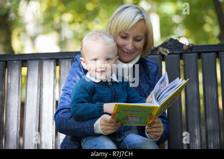 Mutter und Sohn sind ein Buch auf einer Parkbank Stockfoto