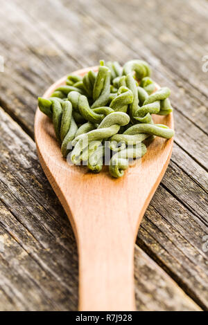 Nicht gegartem Spinat gemelli Pasta in Löffel aus Holz. Stockfoto