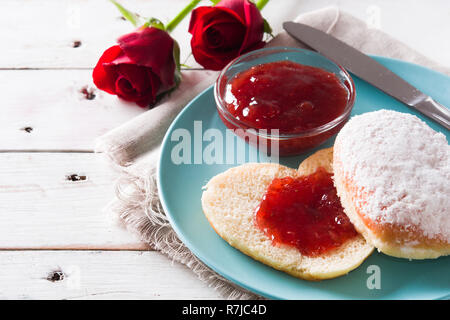 Romantisches Frühstück mit Herzförmigen bun- und Berry jam auf weissem Holztisch. Nahaufnahme Stockfoto