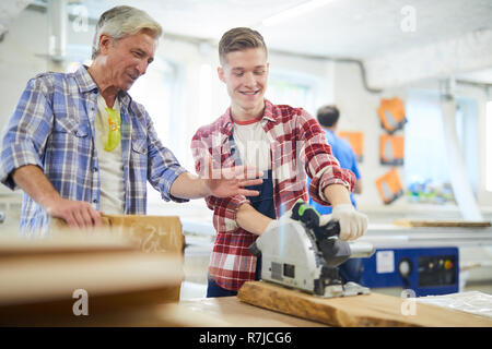 Positive junge zimmerei Student mit Kreissäge auf Klasse Stockfoto