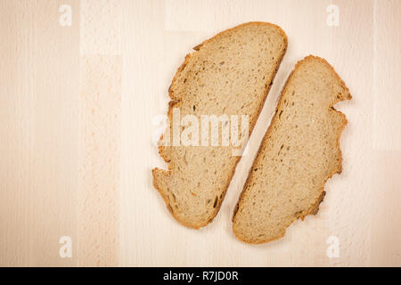 Zwei Scheiben ein typisch deutsches Brot liegen auf einem Holz Buche Tisch. Closeup Schuß von oben. Dieses Brot besteht aus 50 % Roggen. Es hat eine knusprige Kruste. Stockfoto