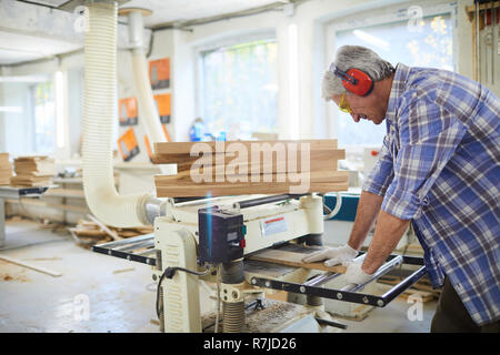 Konzentriert Tischler arbeiten mit holzbrett an Maschine Stockfoto