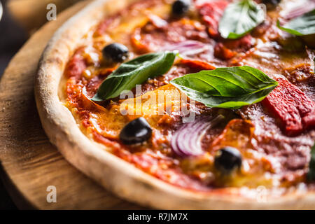 Pizza diavolo traditionelle italienische Speisen aus würzigen Salami Peperoni chili Zwiebel Oliven und Basilikum. Stockfoto