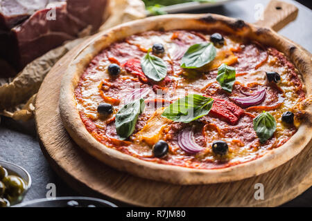 Pizza diavolo traditionelle italienische Speisen aus würzigen Salami Peperoni chili Zwiebel Oliven und Basilikum. Stockfoto