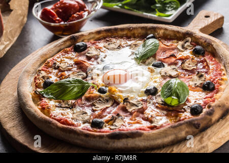 Pizza Capricciosa capricious traditionelle italienische Speisen aus Schinken Champignons Artischocken Eiern parmesan Oliven und Basilikum. Stockfoto