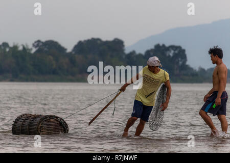 Don Daeng, Laos - 27. April 2018: Zwei Männer in der Dämmerung Fische fangen in einer abgelegenen Insel des Mekong in Laos. Stockfoto