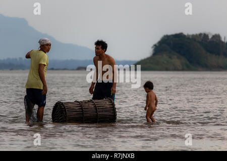 Don Daeng, Laos - 27. April 2018: Zwei Männer und ein Kind in der Dämmerung Fische fangen in einer abgelegenen Insel des Mekong in Laos. Stockfoto