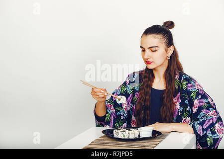 Schöne Mädchen essen Sushi in einem Studio Stockfoto