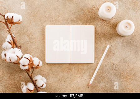 Notebook mit weißen Stift unter Baumwolle Blumen und weißen Kerzen geöffnet. Flach, Ansicht von oben, bis cmock. Das Konzept der Planung und Ziele zu setzen Stockfoto